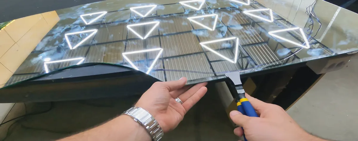 Mãos destacando o espelho cortado à mão no terceiro desafio da Arena do Vidro